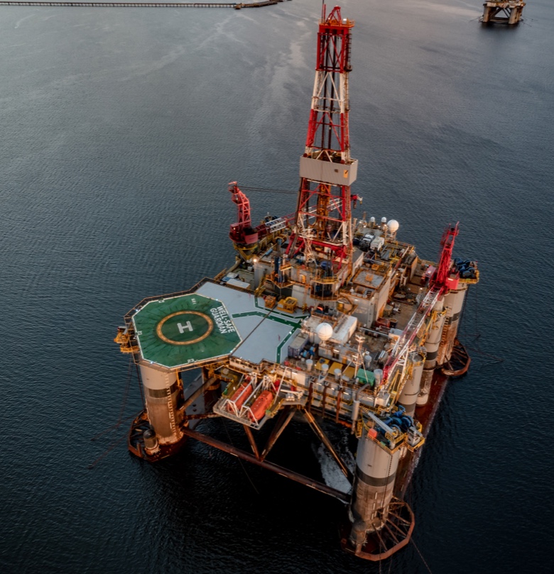 Aerial photo of an oil rig in the sea with a helicopter landing pad